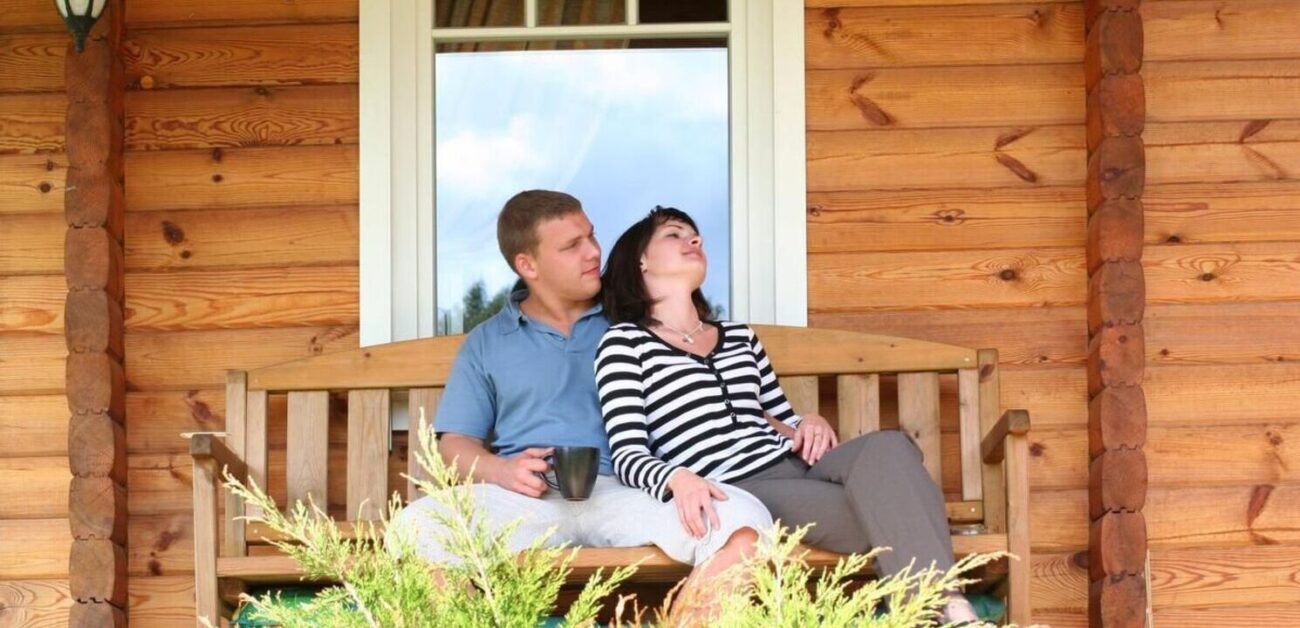 Para siedzi przy drewnianym domu